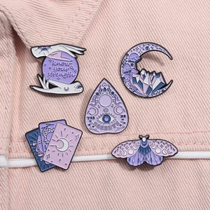 Détail de cinq broches en émail aux motifs mystiques de cristal et lune sur jean rose