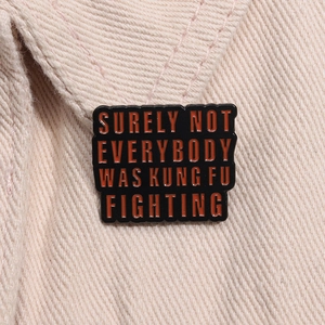 Macro detail of black enamel pin with red slogan on corduroy fabric texture