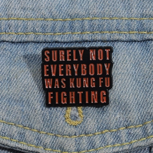 Detail of square enamel brooch with Kung Fu Fighting text on blue denim jacket pocket