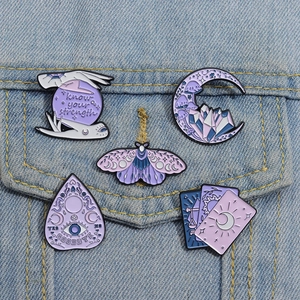Détail de cinq pin's mystiques en émail violet épinglés sur une veste en jean