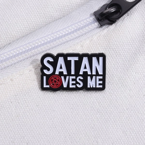 Black enamel pin with Satan Loves Me text and red pentagram on white canvas background