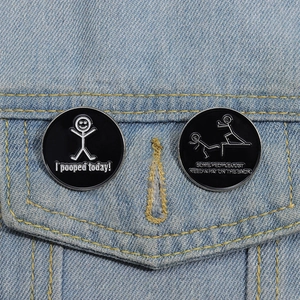 Detailed view of funny stick figure enamel pins pinned to a blue denim jacket pocket