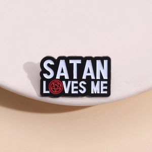 Minimalist black enamel pin featuring Satan Loves Me text on a white pedestal