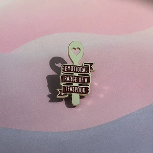 Détail du pin's cuillère émaillé vert avec ruban bordeaux et citation motivante
