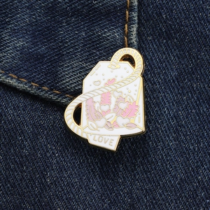 Nahaufnahme der Emaille-Teebeutel-Brosche mit Blumenmuster und LOVE-Tag auf Denim