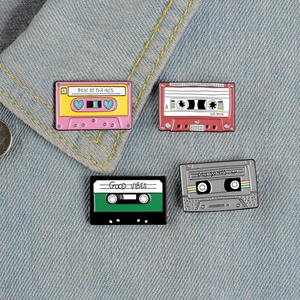 Set of four retro enamel cassette tape brooches pinned on denim jacket for 90s style