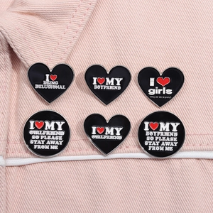 Detail of enamel lapel pins with heart slogans on pink denim fabric background