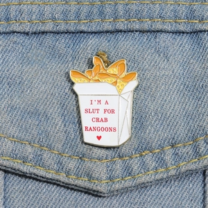 Dettaglio della spilla smaltata box Crab Rangoon sulla tasca di jeans blu