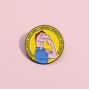 Détail d'un pin's en émail avec un dinosaure rose en pose d'ouvrière et un slogan gravé
