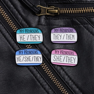 Macro detail of four colorful enamel nameplate pins on a textured black leather jacket