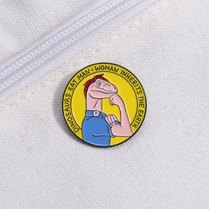 Macro d'un pin's dinosaure jaune en émail posé sur un sac en toile blanche texturée