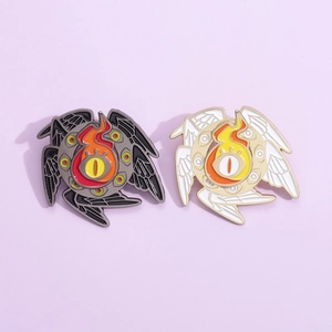 Detail view of gothic enamel pins featuring mystical eye flames and wings in two colors