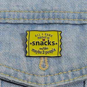 Yellow enamel snack bag pin with funny quote on a blue denim jacket background