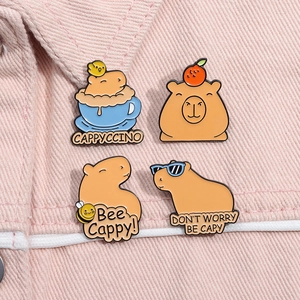Set of four cute capybara enamel pins including a cappuccino and bee design on denim fabric
