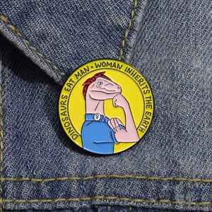 Détail d'un pin's dinosaure rose sur veste en jean avec citation du film Jurassic Park