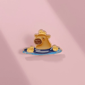 Cute capybara and duckling enamel pin badge with golden metal edges on pink background