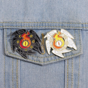 Enamel pins with Eye of Horus wings and flames on denim jacket pocket