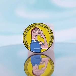 Broche ronde en émail motif dinosaure style Rosie la riveteuse sur fond bleu clair