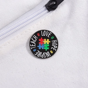 Round colorful puzzle enamel pin with Teach Love Hope Inspire text on white canvas