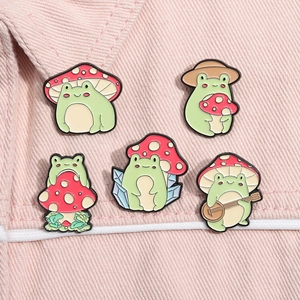 Detailed view of 5-piece set of cartoon frog enamel pins with red mushroom caps