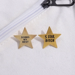 Set of two gold five-pointed star metal badges with text on a white canvas bag
