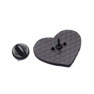 Dettaglio del retro della spilla nera a forma di cuore con texture e chiusura in gomma