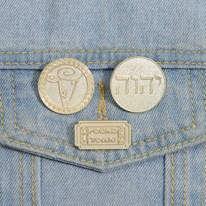 Macro shot of gold geometric brooches pinned on a light blue denim jacket pocket