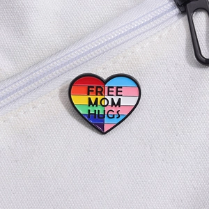 Dettaglio della spilla smaltata a cuore arcobaleno con scritta Free Mom Hugs su borsa