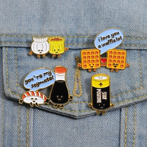 Détail de quatre épinglettes créatives en émail sur denim incluant gaufre et sushi mignon