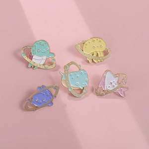 Close-up of enamel pins featuring ocean creatures with golden star rings on pink background
