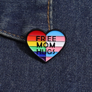 Dettaglio della spilla a cuore Free Mom Hugs su una tasca di giacca in denim blu