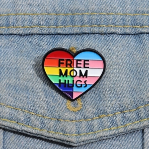 Dettaglio della spilla a cuore Free Mom Hugs con motivo arcobaleno su jeans denim