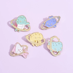 Detail view of five marine creature enamel pins with planetary rings in pastel colors