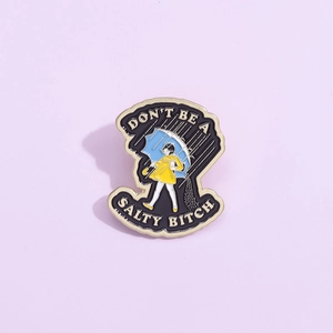 Enamel pin featuring Morton Salt girl parody with Don't Be A Salty Bitch text