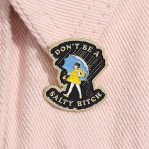 Close-up of a girl in yellow raincoat enamel pin on pink denim fabric with text