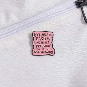 Detail of pink enamel letter brooch with humorous English quote on white canvas bag