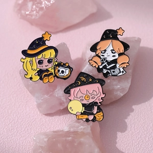 Detailed view of three cute cartoon witch enamel pins displayed on pink crystal stands