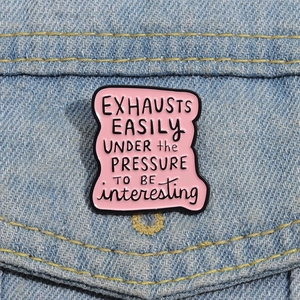 Close-up of pink enamel letter pin on denim fabric with creative minimalist text