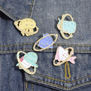 Detailed set of five cartoon ocean creature enamel pins on blue denim fabric