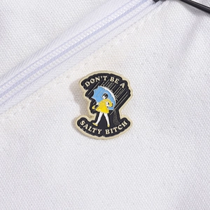 Funny enamel pin featuring a girl with umbrella and slogan on white canvas fabric