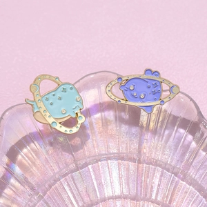 Detail of cute enamel pins featuring ocean creatures with starry rings on pastel background