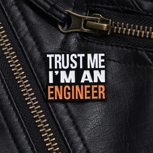 Close-up of Trust Me I'm an Engineer enamel pin on a black leather jacket texture