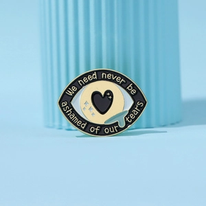 Broche en émail en forme d'œil avec larmes et texte inspirant sur fond bleu doux