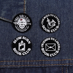 Detail of four dark gothic enamel pins on denim, featuring skulls and romantic tropes