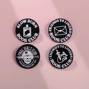 Macro shot of 4 metal enamel pins with black and white gothic horror film club designs
