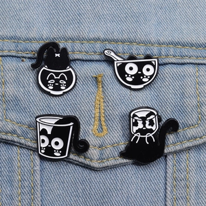 Lot de quatre épingles en émail chat noir mignonnes sur une veste en jean bleue