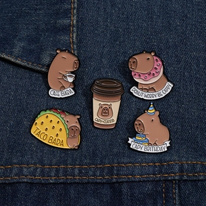 Detailed close-up of 5 enamel capybara pins with food themes on dark denim fabric