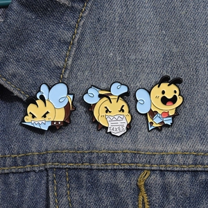 Detailed macro view of three enamel bee brooches with TAXES motif on blue denim fabric