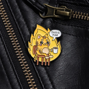 Detail of 'This Is Fine' enamel pin with fire design on black leather jacket