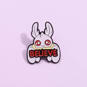 Mini creative mothman enamel pin with red believe text on a soft purple background